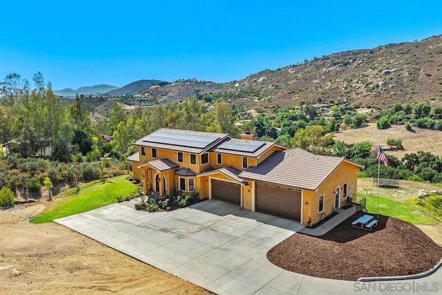 view of front of property with a mountain view, a garage, and solar panels