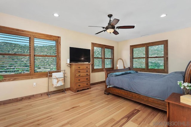 bedroom with ceiling fan, light hardwood / wood-style floors, and multiple windows