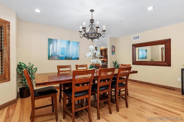 dining area with light wood-type flooring and a notable chandelier