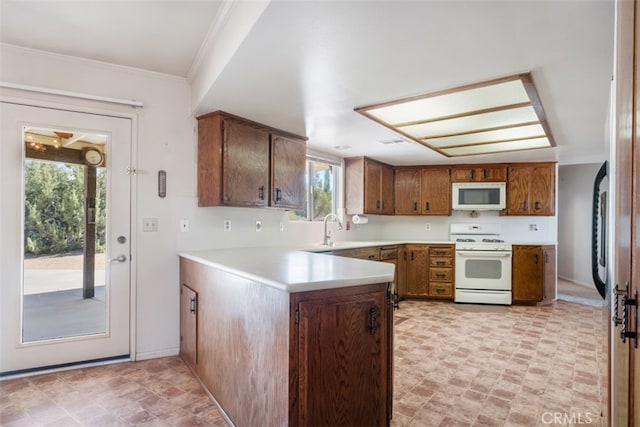 kitchen featuring crown molding, white appliances, sink, and kitchen peninsula