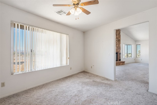 carpeted spare room with lofted ceiling, ceiling fan, and a fireplace