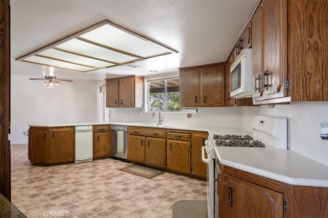 kitchen with kitchen peninsula, white appliances, ceiling fan, and sink