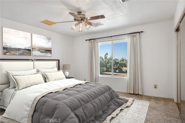 bedroom with light carpet, a closet, ceiling fan, and a textured ceiling