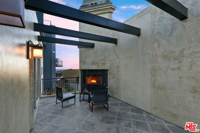 patio terrace at dusk featuring exterior fireplace