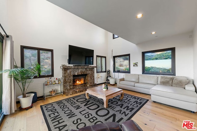 living room with light hardwood / wood-style floors, a high end fireplace, and a healthy amount of sunlight