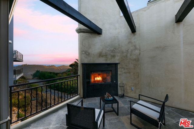 balcony at dusk with exterior fireplace