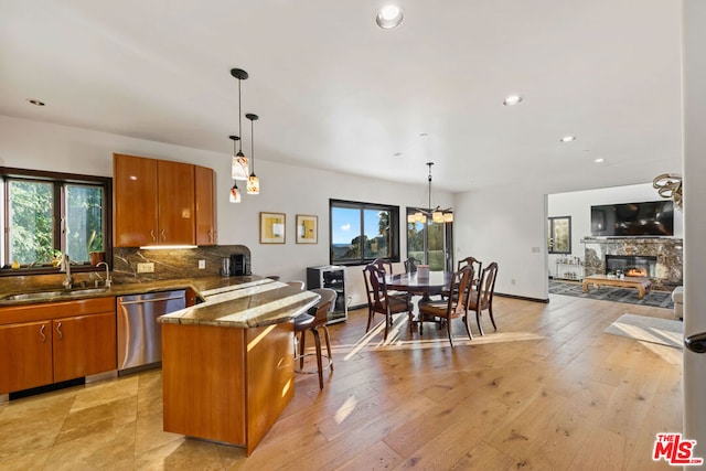 kitchen featuring stainless steel dishwasher, decorative light fixtures, sink, and a kitchen breakfast bar