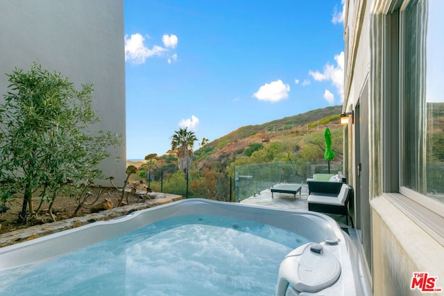 view of swimming pool featuring a mountain view and a hot tub