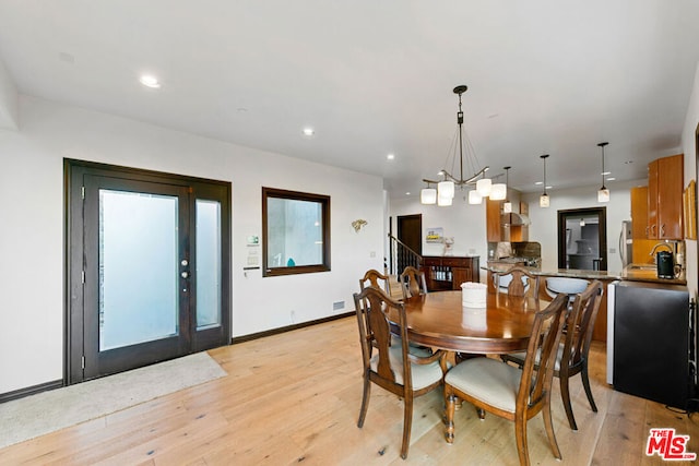 dining space featuring light wood-type flooring and a notable chandelier