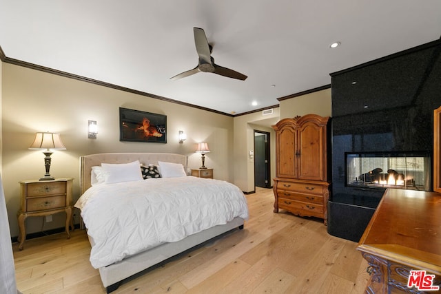 bedroom with ceiling fan, ornamental molding, a multi sided fireplace, and light hardwood / wood-style flooring