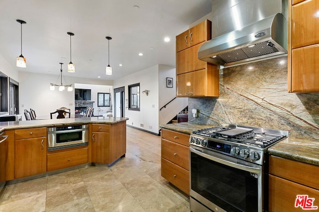 kitchen featuring stainless steel appliances, backsplash, decorative light fixtures, dark stone counters, and wall chimney exhaust hood