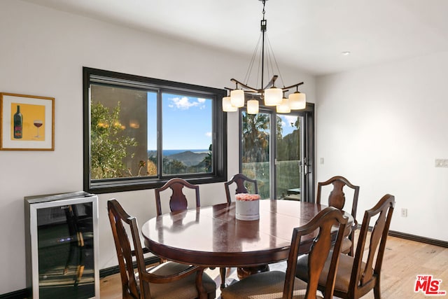 dining room with a chandelier, light hardwood / wood-style floors, and beverage cooler