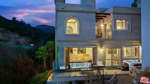 back house at dusk with a mountain view and a balcony