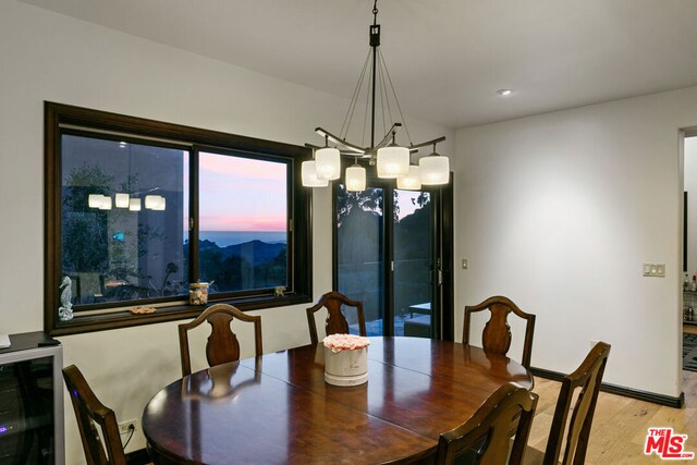 dining space featuring beverage cooler, light hardwood / wood-style flooring, and a notable chandelier