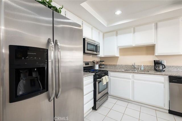 kitchen with light tile patterned flooring, sink, white cabinets, appliances with stainless steel finishes, and light stone countertops