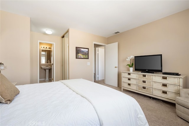 bedroom featuring ensuite bath and carpet