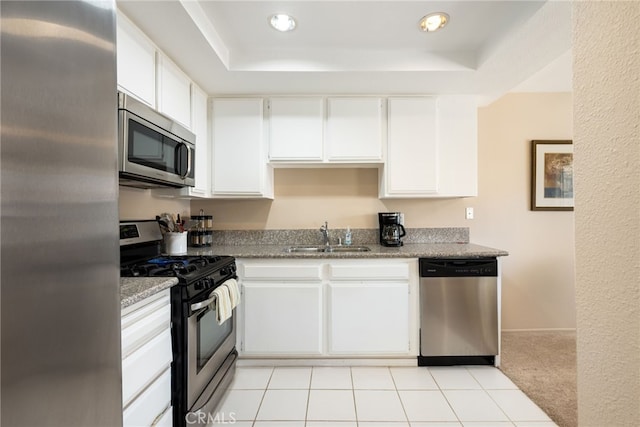 kitchen with white cabinetry, light stone counters, stainless steel appliances, sink, and light carpet