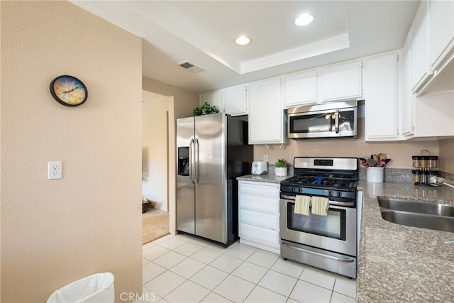 kitchen featuring light tile patterned floors, sink, white cabinetry, stainless steel appliances, and a tray ceiling