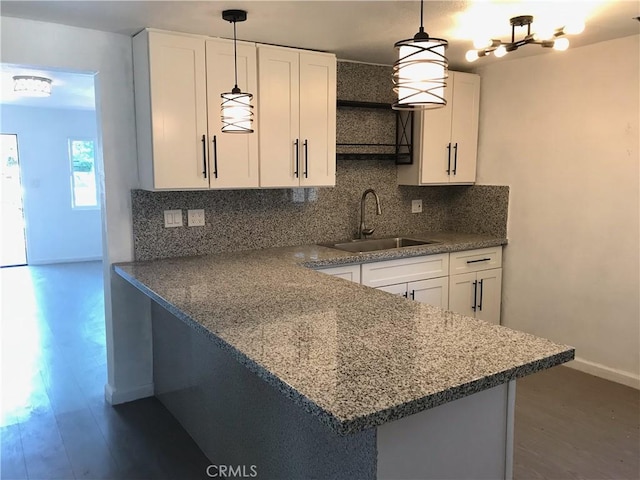 kitchen with decorative backsplash, sink, pendant lighting, and white cabinets