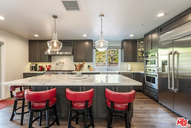 kitchen featuring dark wood-type flooring, a center island, stainless steel appliances, and dark brown cabinets