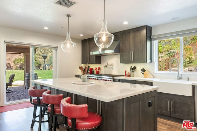 kitchen with a center island, sink, light hardwood / wood-style floors, dark brown cabinetry, and extractor fan