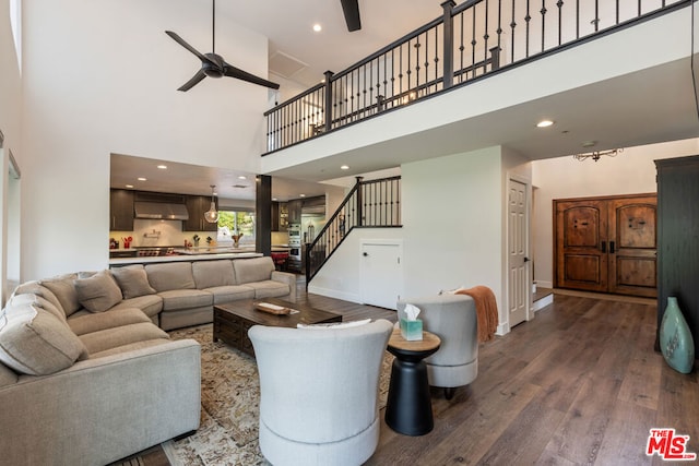 living room with hardwood / wood-style floors, ceiling fan, and a towering ceiling