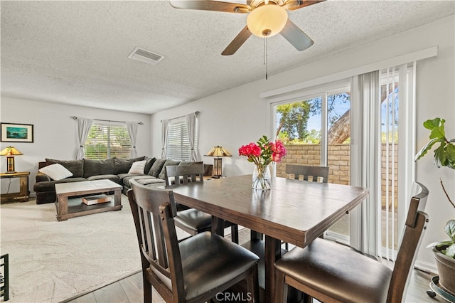 dining space with a textured ceiling, ceiling fan, and light hardwood / wood-style flooring