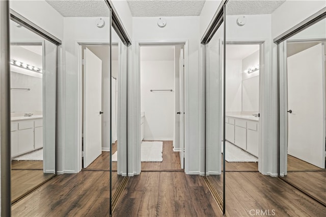 unfurnished bedroom featuring a textured ceiling, ensuite bath, and dark hardwood / wood-style flooring