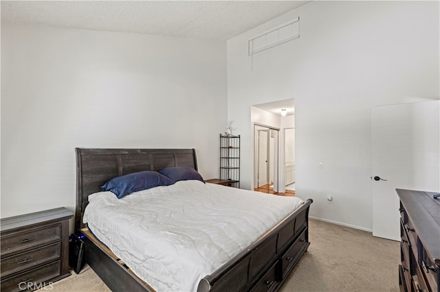 carpeted bedroom with a textured ceiling, a closet, and a high ceiling