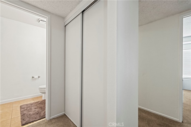 interior space with tile patterned flooring, a textured ceiling, and toilet