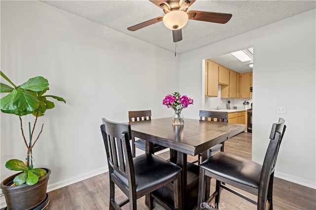 dining area with ceiling fan, a textured ceiling, sink, and hardwood / wood-style floors