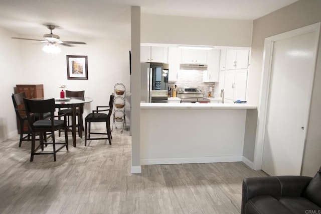 kitchen with appliances with stainless steel finishes, backsplash, ceiling fan, light hardwood / wood-style flooring, and white cabinetry