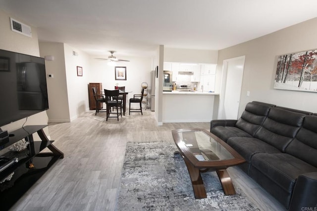 living room with light hardwood / wood-style floors and ceiling fan