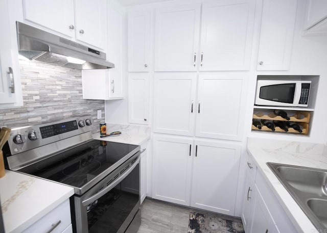 kitchen with decorative backsplash, white microwave, sink, electric range, and white cabinets