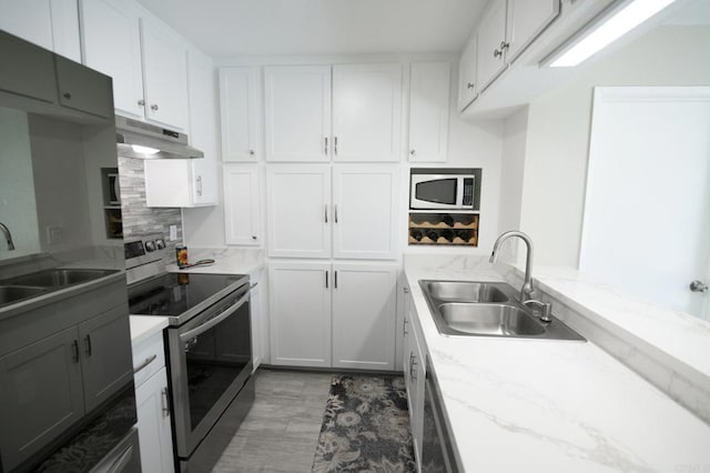 kitchen featuring white cabinetry, sink, white microwave, and stainless steel electric range