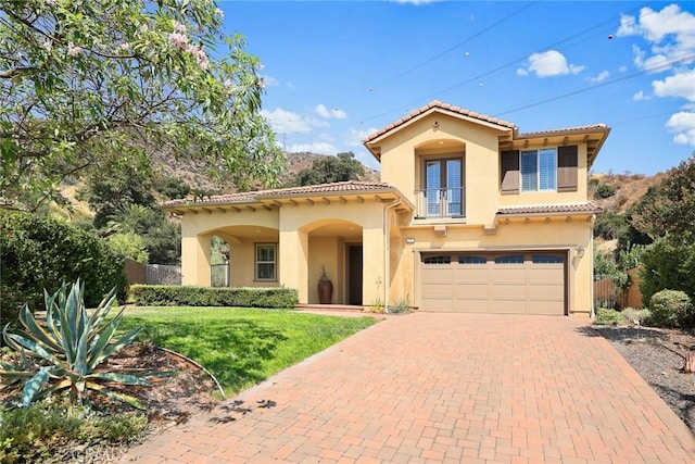 mediterranean / spanish-style home featuring a garage and a front lawn