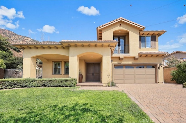 mediterranean / spanish house with a balcony, a front yard, and a garage