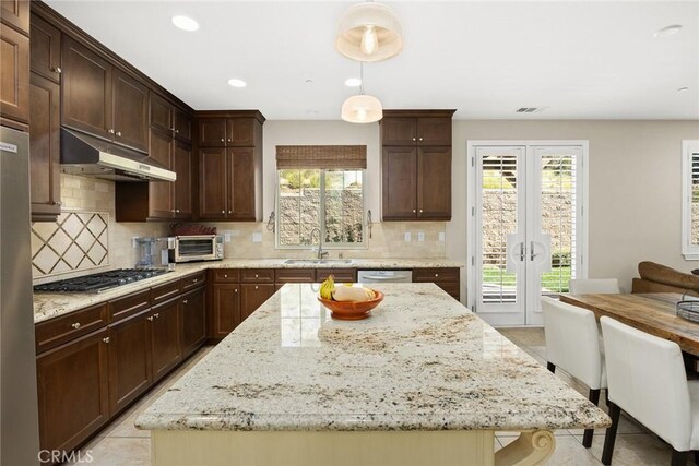 kitchen featuring under cabinet range hood, stainless steel appliances, a wealth of natural light, and a sink