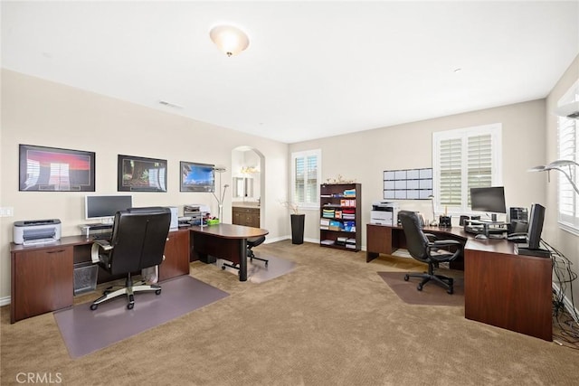 office featuring baseboards, arched walkways, and carpet floors