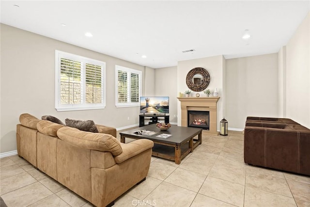 living area with light tile patterned floors, baseboards, visible vents, recessed lighting, and a warm lit fireplace