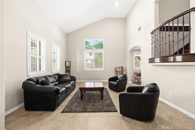 tiled living room with visible vents, baseboards, arched walkways, and stairs