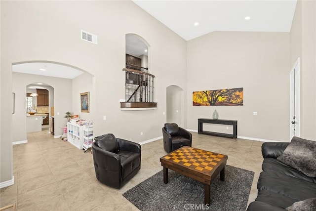 living room with light tile patterned floors, visible vents, high vaulted ceiling, and baseboards