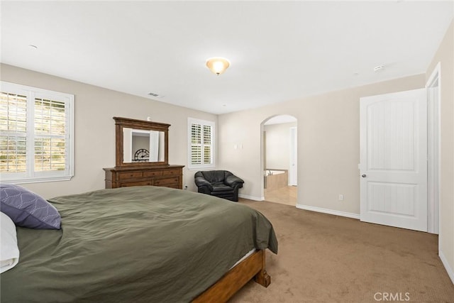 bedroom featuring baseboards, arched walkways, carpet floors, and connected bathroom