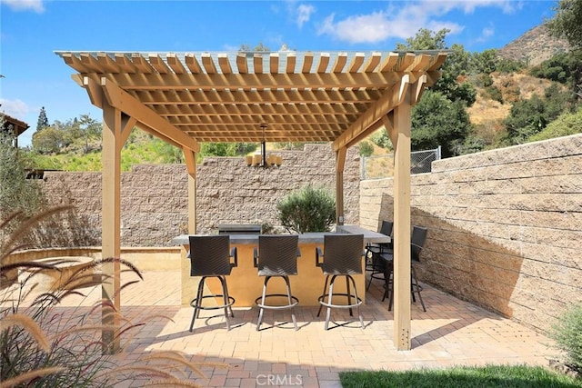 view of patio / terrace featuring outdoor dry bar, a pergola, and a fenced backyard