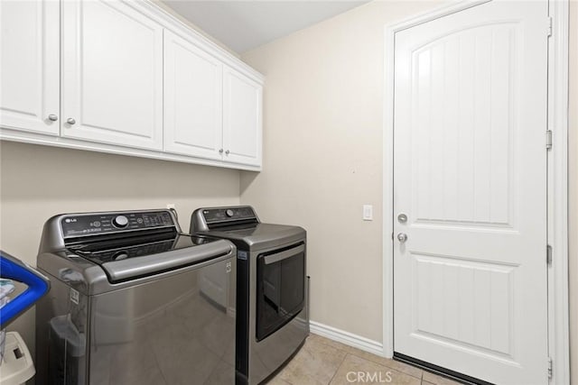 laundry area featuring washing machine and clothes dryer, cabinet space, baseboards, and light tile patterned flooring