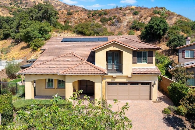 mediterranean / spanish-style home featuring solar panels and a garage