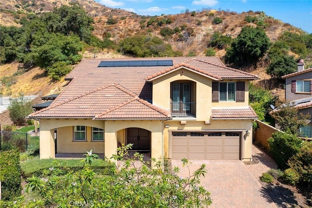 mediterranean / spanish home with fence, stucco siding, french doors, a tiled roof, and decorative driveway