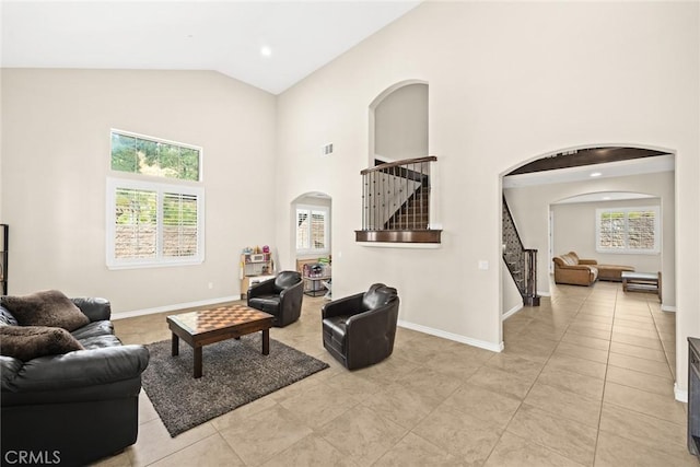 living room with stairway, baseboards, arched walkways, and high vaulted ceiling