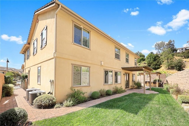 rear view of house with fence, a yard, a pergola, stucco siding, and central air condition unit