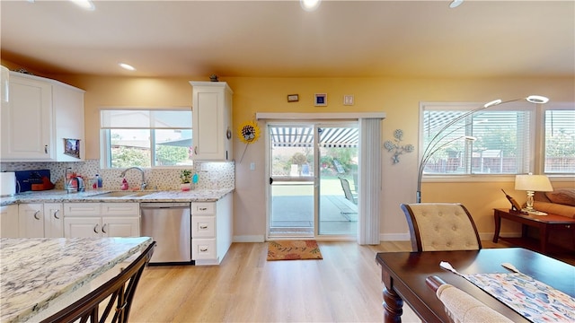 kitchen featuring dishwasher, white cabinets, sink, decorative backsplash, and light stone countertops